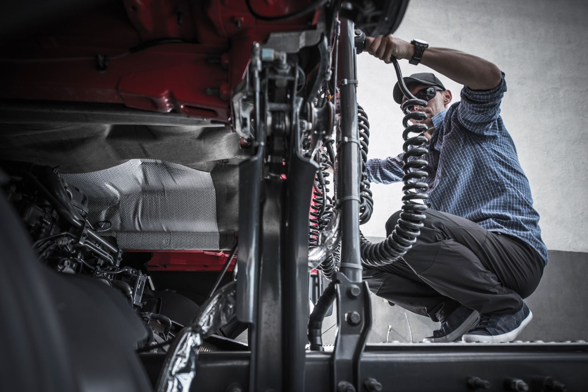 A man is working on the underside of a truck. A man is working on the underside of a truck.